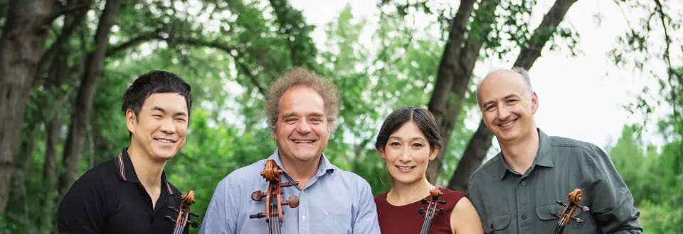 The Takacs Quartet standing with trees behind them.