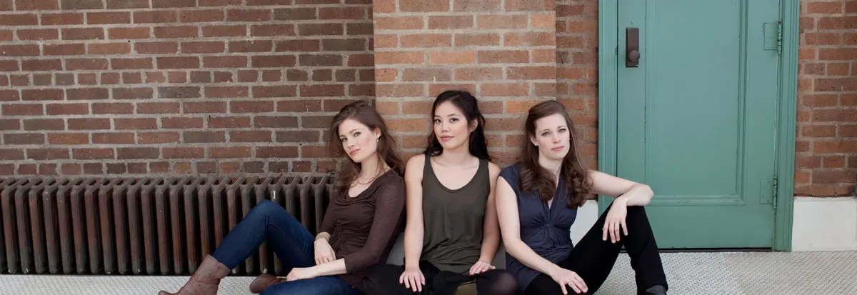 Members for the Claremont Trio sitting in front of a brick building
