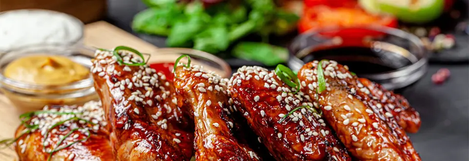American cuisine. Fried chicken wings with tomato sauce and sesame seeds. 