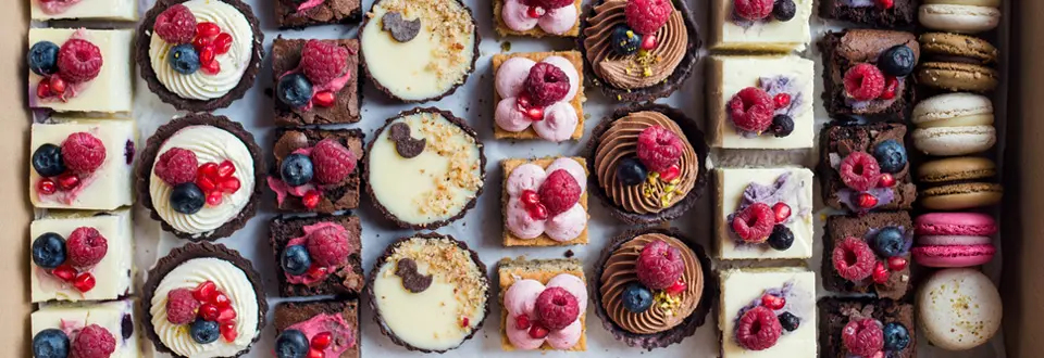 Top view of selection of colorful and delicious cake desserts in box.