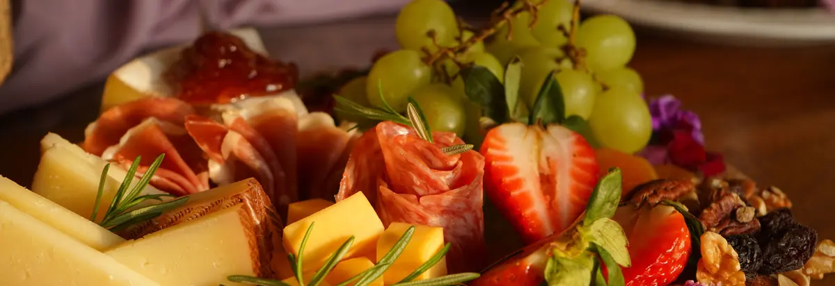 An elegant arrangement of cheese, cured meats, fruits, and nuts on a wooden board, perfect for gourmet dining.